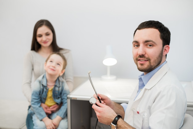 Doctor examining little girl with her mother in medical office