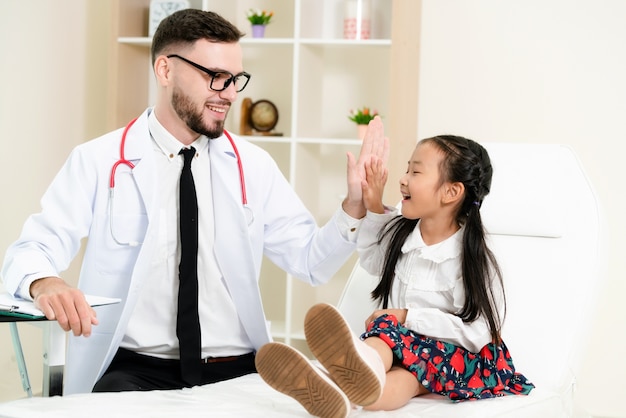 Doctor examining little happy kid in hospital.