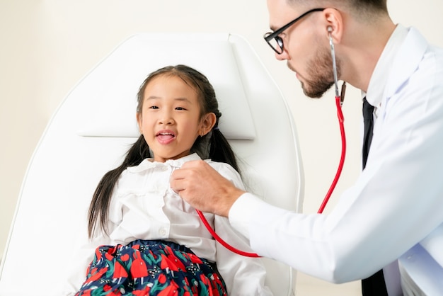 Doctor examining little happy kid in hospital.