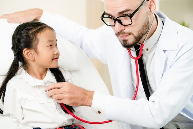 Doctor examining little happy kid in hospital.