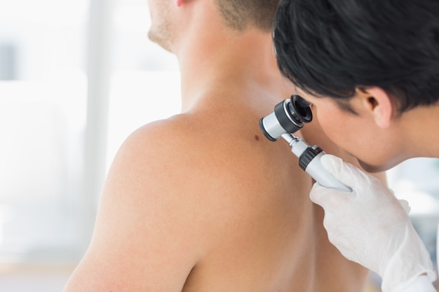 Doctor examining mole on back of man