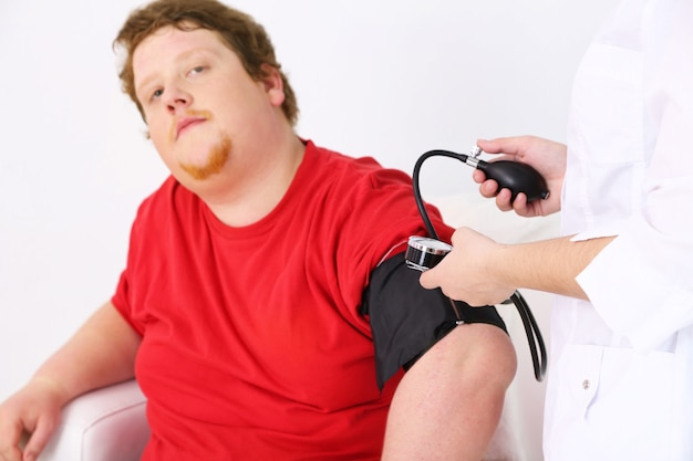 Doctor examining  patient obesity on light background