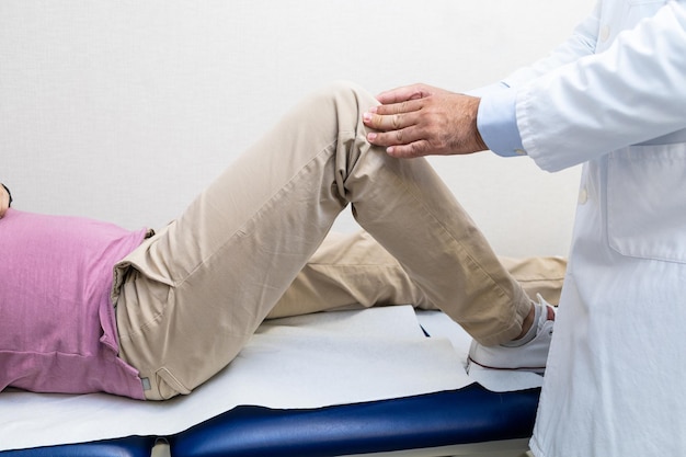 doctor examining patients knee in clinic
