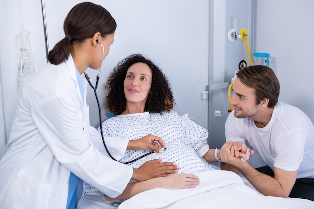 Doctor examining pregnant woman in ward