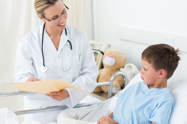 Doctor examining report of sick boy