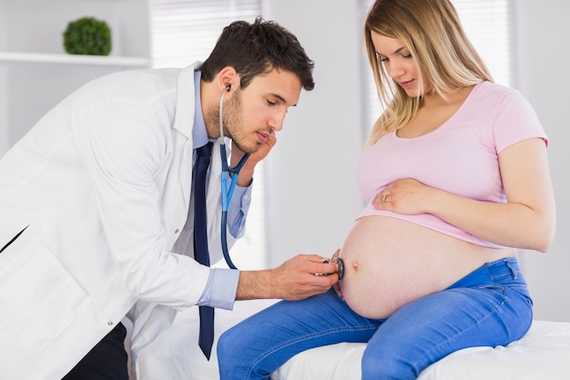 Doctor examining stomach of pregnant patient