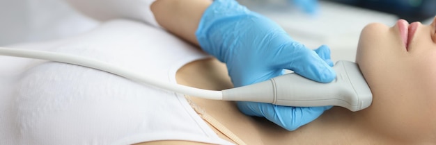 Doctor examining thyroid of female patient with ultrasound scan in clinic