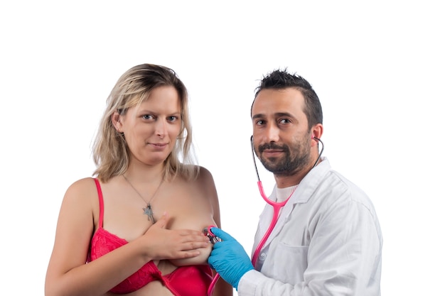 Врач осматривает женскую грудь со стетоскопом на наличие шишек или других аномалий