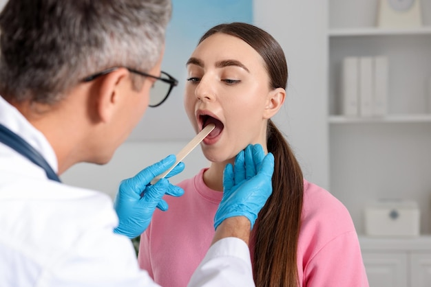 doctor examining woman39s throat with tongue depressor in clinic
