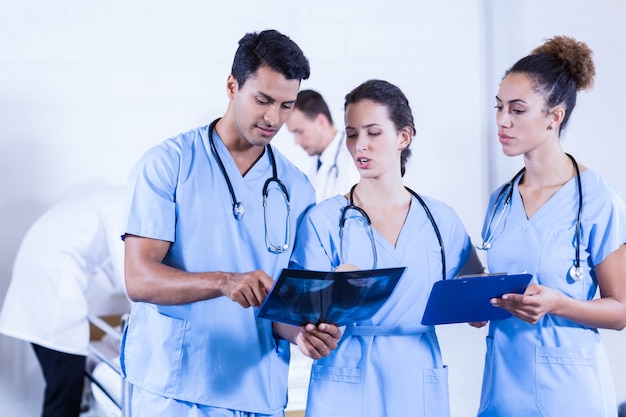 Doctor examining an x-ray in hospital and his colleagues having a discussion