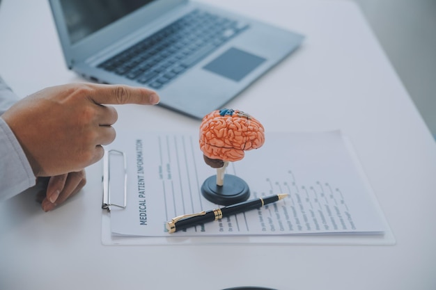 Photo doctor explaining brain functions to patient on model in office