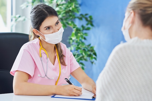 doctor explaining diagnosis to her female patient wearing a mask