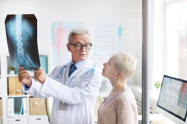 Foto medico che spiega i problemi spinali alla donna anziana