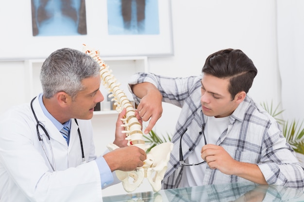 Foto medico che spiega la colonna vertebrale a un paziente