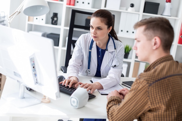 The doctor explains the problem to the patient on the computer.