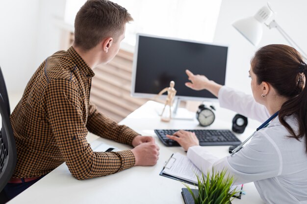 The doctor explains the problem to the patient on the computer.