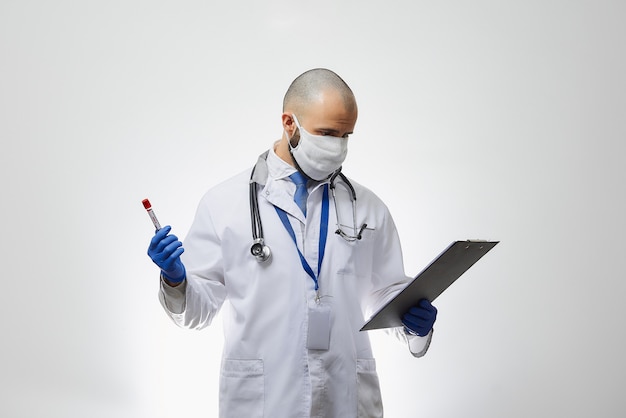 A doctor in a face mask reading information about a coronavirus blood test in his hand.