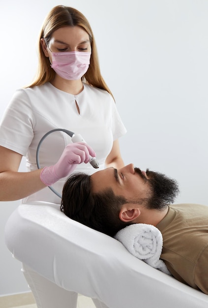 Doctor female dermatologist trichologist makes a procedure to stimulate hair growth on head to a