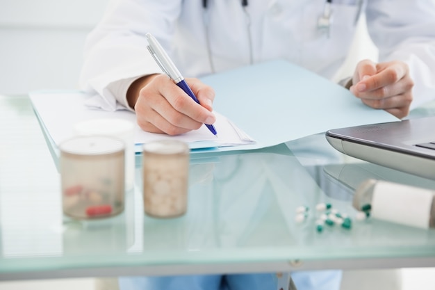 Photo doctor filling out prescriptions