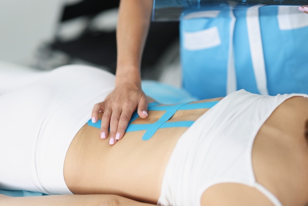 Doctor fixes kinesio tape on spine in patient with back pain