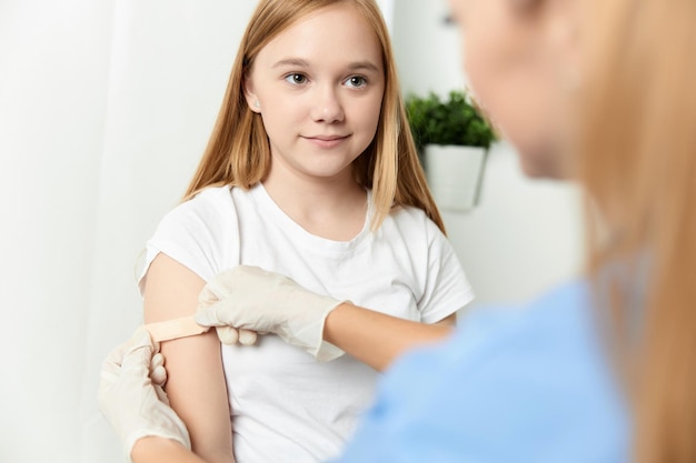 The doctor next to the girl glues her hand with a plaster closeup