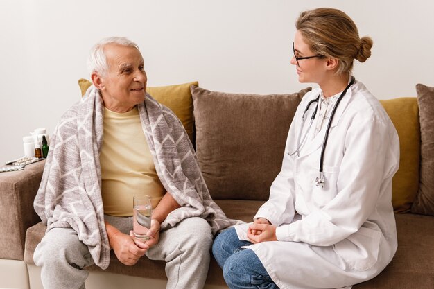 Doctor give a consultation to elderly man during home visit