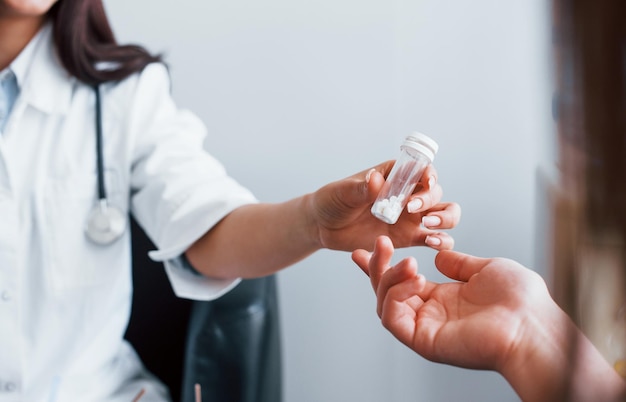 Doctor gives drugs to patient Young woman have a visit with female doctor in modern clinic