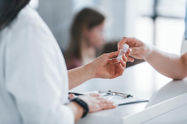 Doctor gives drugs to patient Young woman have a visit with female doctor in modern clinic