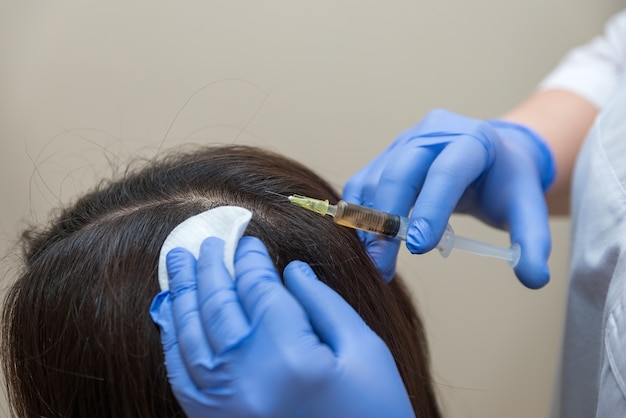 Photo the doctor gives an injection into the scalp for hair growth