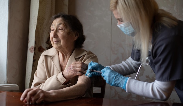 The doctor gives old woman's an injection.