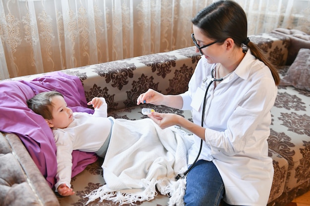 Il medico dà la pillola al bambino. dottoressa a casa. il pediatra fornisce vitamine a un piccolo paziente dopo l'esame.