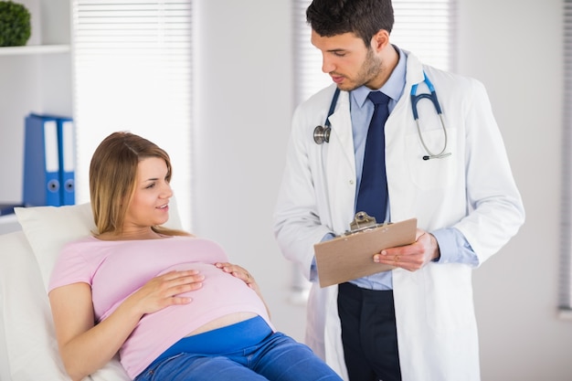 Photo doctor giving advice to lying pregnant patient