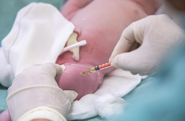 Photo doctor giving first vaccine to newborn