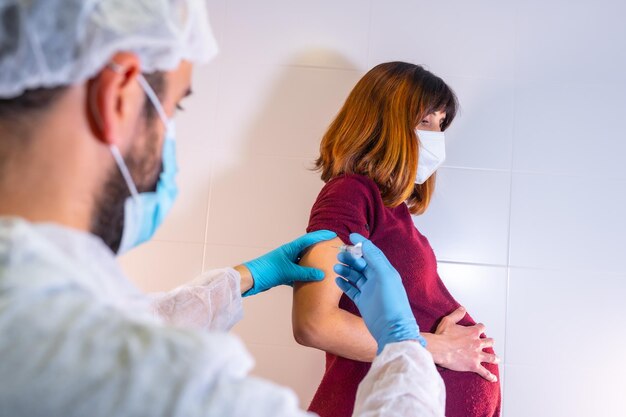 Medico che somministra il nuovo vaccino approvato per le donne in gravidanza contro il coronavirus anticorpi immunizzano la popolazione effetti collaterali rischio persone anticorpi covid19