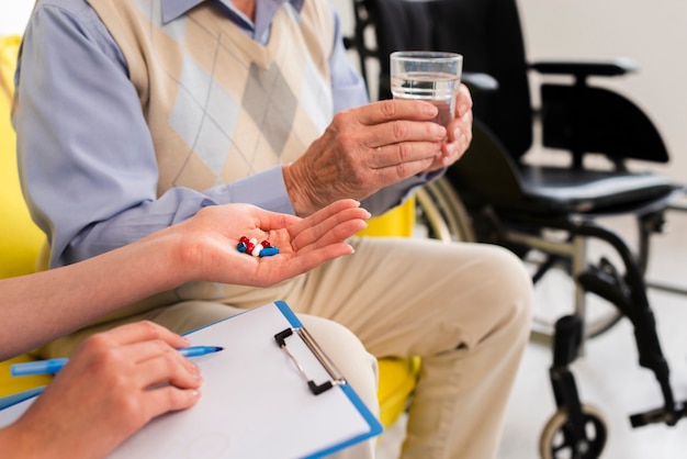 Doctor giving an old man his pills