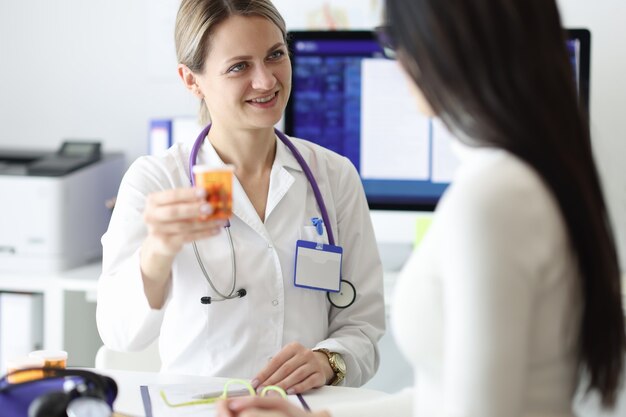 Medico che dà la bottiglia paziente di medicina in clinica.