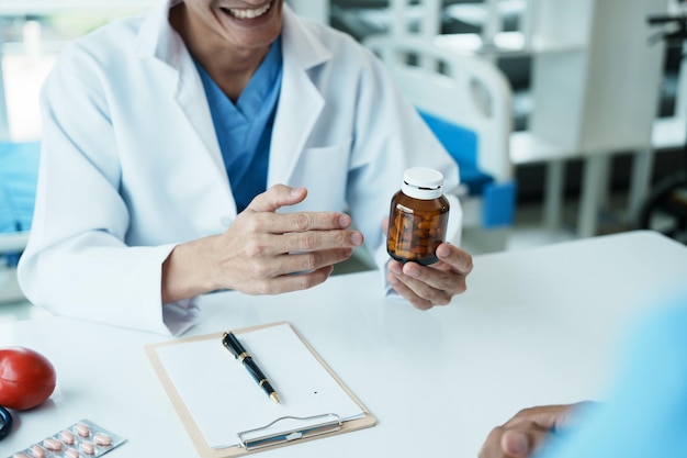 Photo doctor giving prescribing medicine to smiling senior man at meeting in hospital