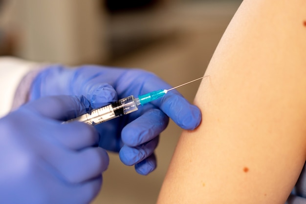 Doctor giving shot or vaccine to a patient. Vaccination and prevention against flu or virus pandemic.