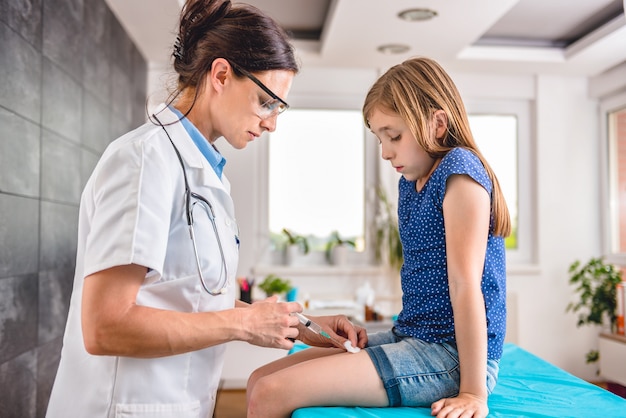 Doctor giving a young girl a vaccine shot