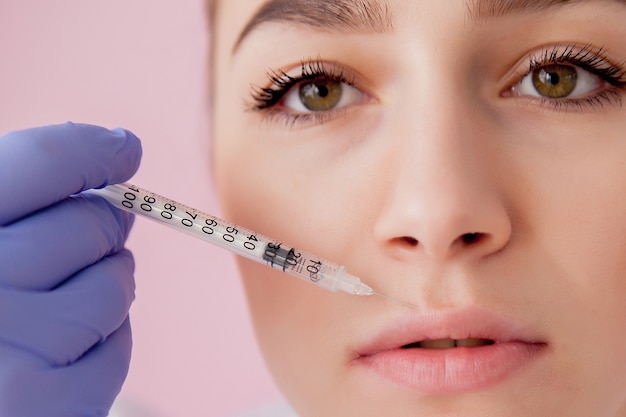 Doctor in gloves giving woman botox injections in lips