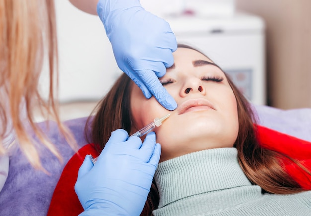 Doctor in gloves  giving woman injections in lips