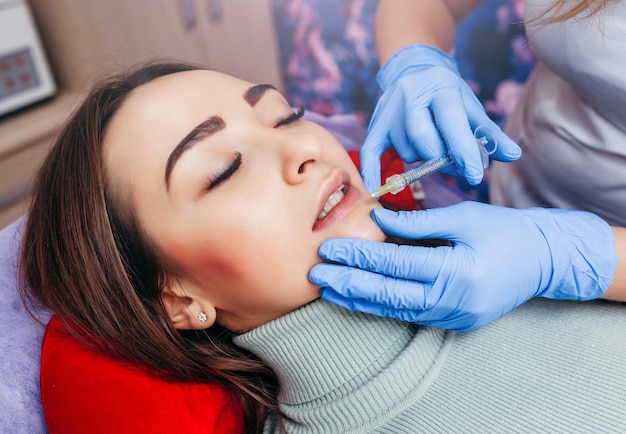 Doctor in gloves  giving woman injections in lips