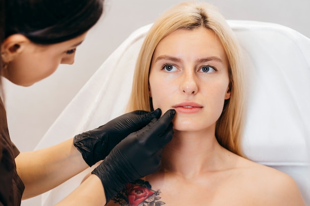 Doctor in gloves  giving woman injections in lips