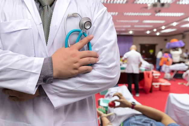 Medico in uniforme dell'abito con lo stetoscopio che sta nella stanza del donatore di sangue