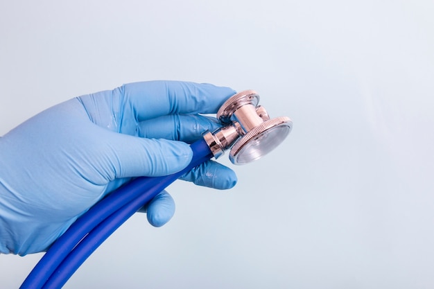 Doctor hand in blue gloves with stethoscope