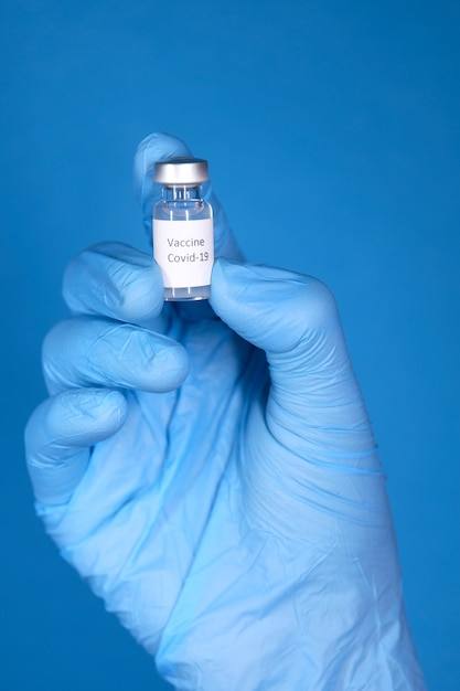 コロナウイルスワクチンを保持している手袋の医者の手、クローズアップ