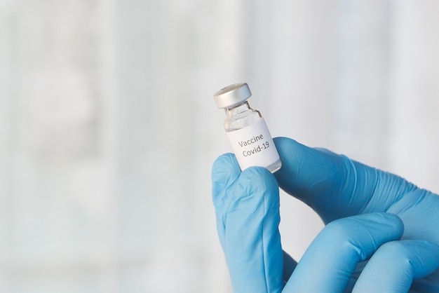 doctor hand in gloves holding coronavirus vaccine, close up