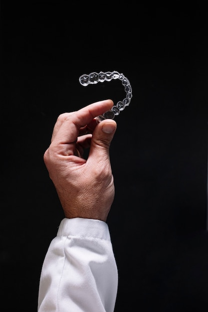 Doctor hand holding a clear dental aligner