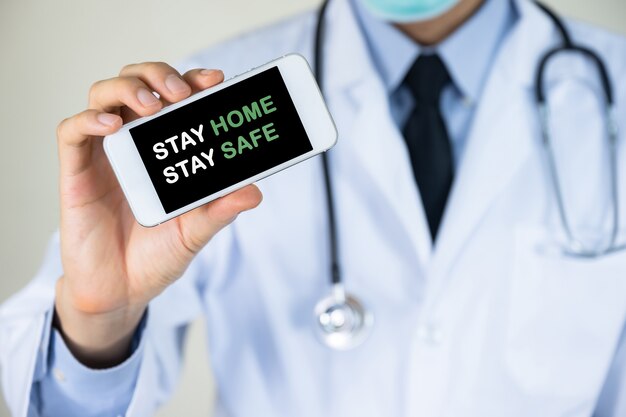 Доктор рука мобильный телефон с пребыванием дома оставаться в безопасности сообщение