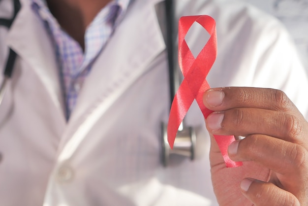 Doctor hand holding red HIV ribbon with copy space